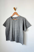 Gray t-shirt on a wooden hanger against a white wall